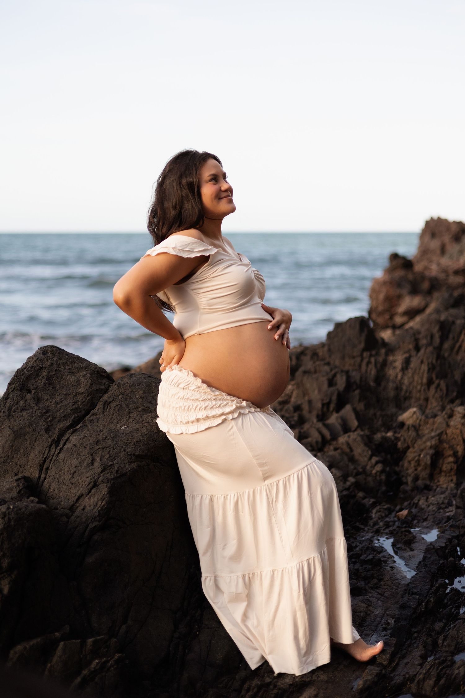 Mum holding her bump during maternity session at Taylors Mistake during sunset Christchurch