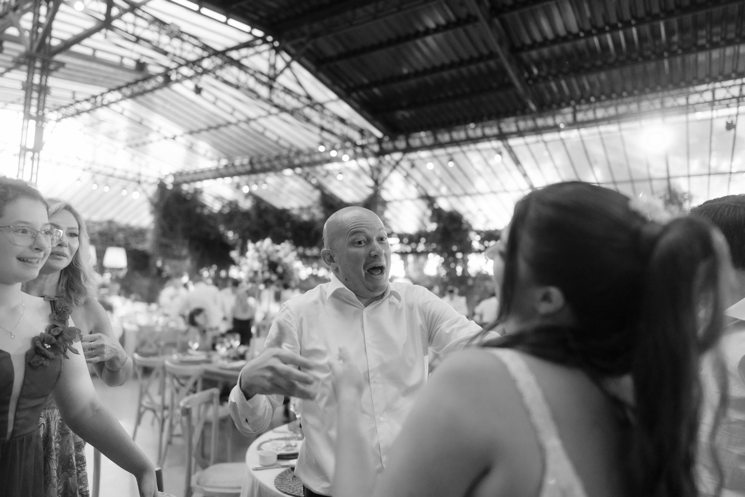 Black and white photo of wedding guests embracing and celebrating on the dance floor.