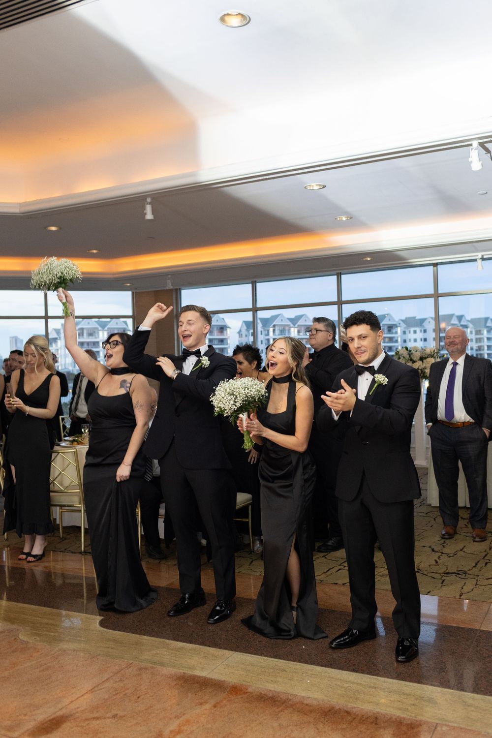 Bridesmaids and groomsmen cheering during the bouquet toss at a luxury Glen Island Harbour Club wedding reception.