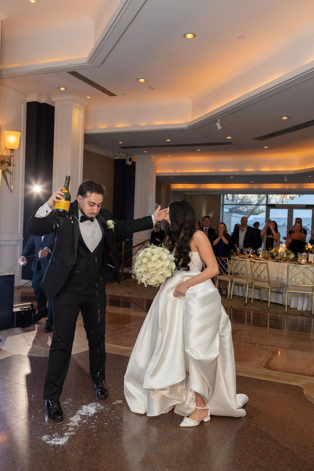 Bride and groom celebrating their wedding reception entrance with champagne at Glen Island Harbour Club in New Rochelle.