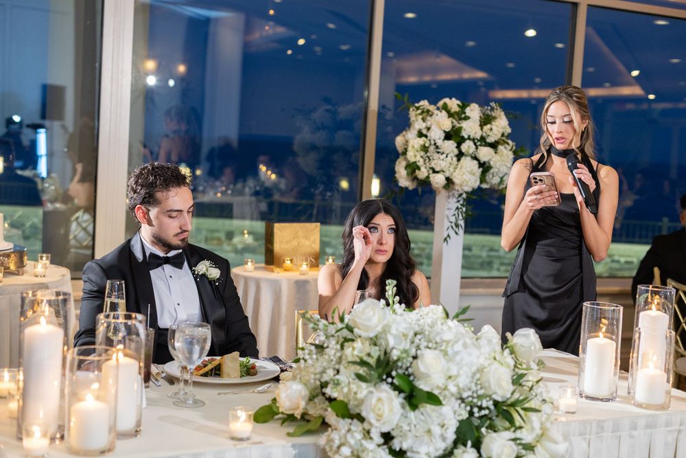 Maid of honor giving an emotional wedding speech while the bride listens during a waterfront reception in New Rochelle.