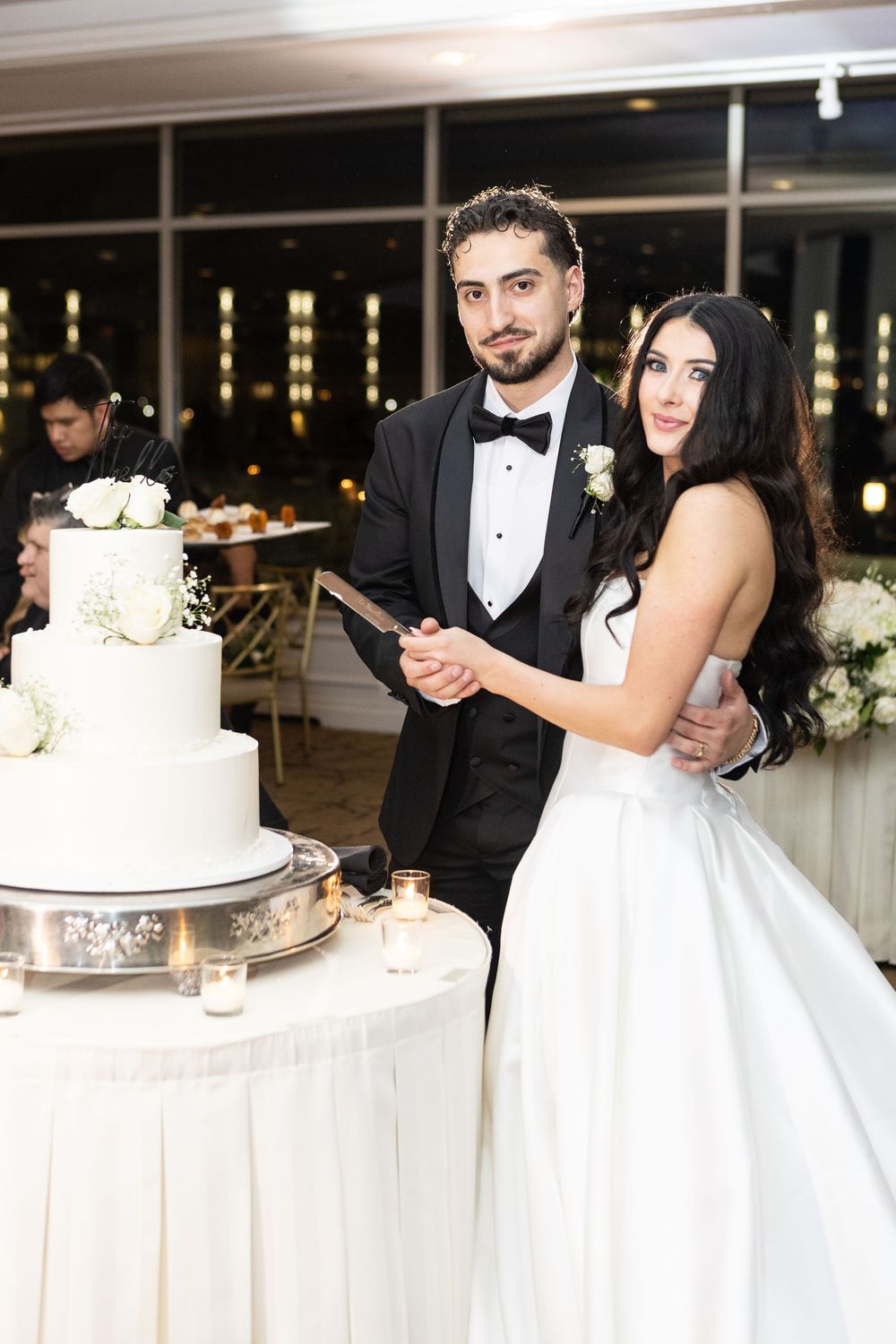 Bride and groom cutting their elegant white wedding cake during a Glen Island Harbour Club wedding reception in New York.