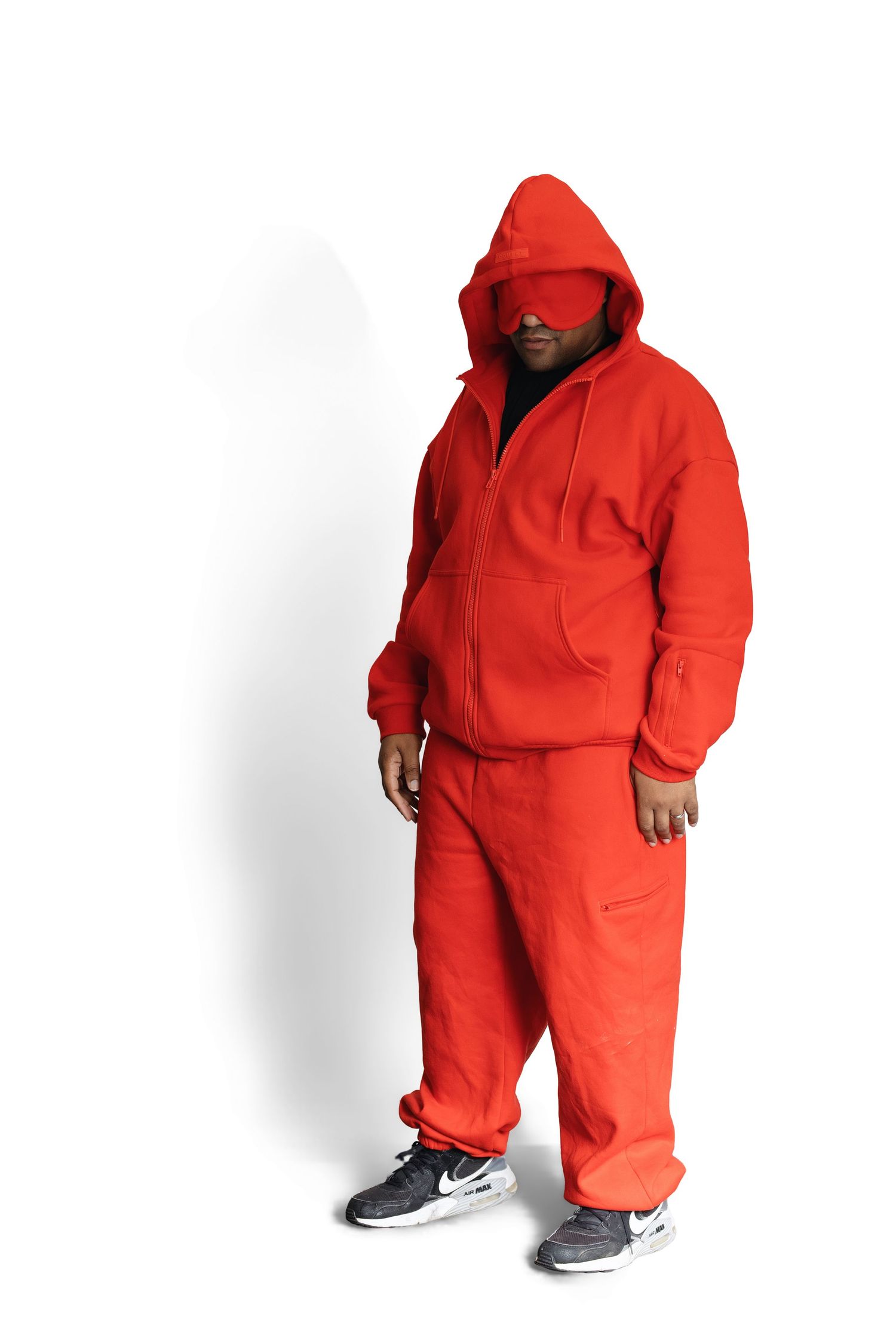 Man wearing a full red hoodie tracksuit with gray Nike sneakers, posing against a white background.