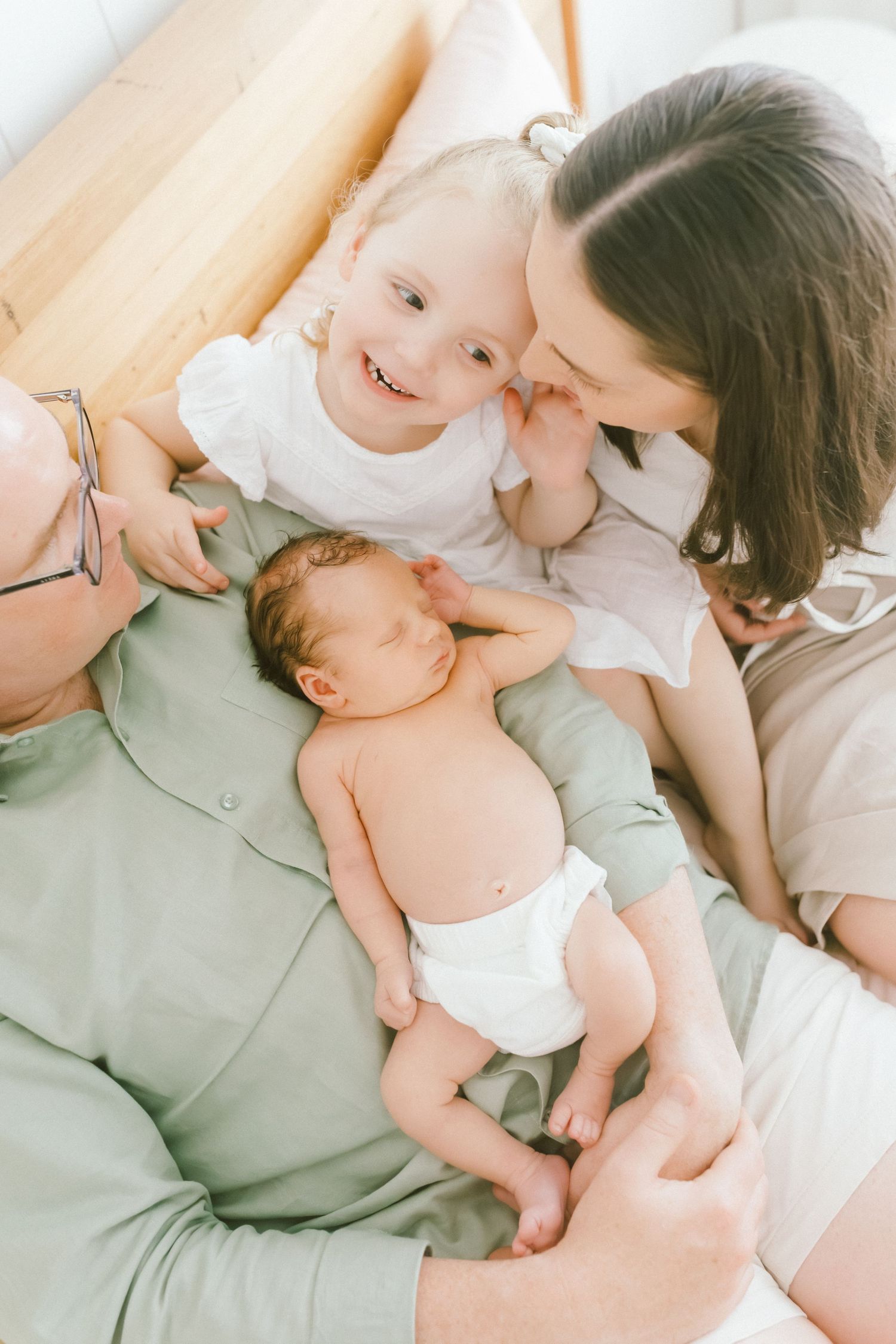 Newborn baby in diaper lying between parents during an intimate family lifestyle newborn photography session.