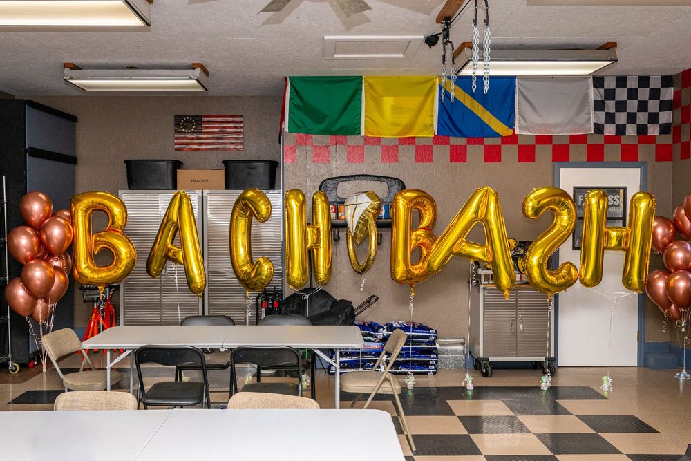 Gold BACH BASH balloon letters displayed in a decorated party room with colorful flags and rose gold balloons.
