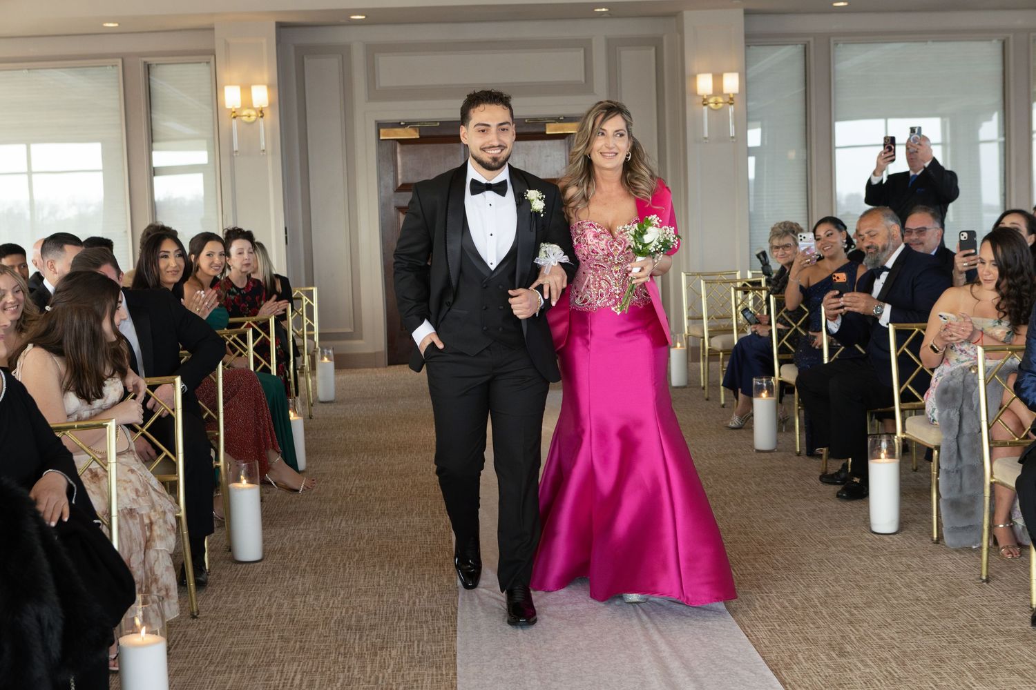 Groom walking down the aisle with his mother during an elegant waterfront wedding ceremony in Westchester, New York.