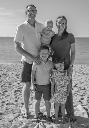 A black and white family photo on the beach.