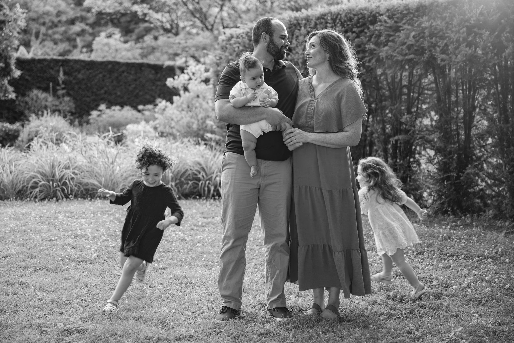 Kids run around parents in black and white.