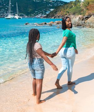 A mother leads her daughter down the beach.