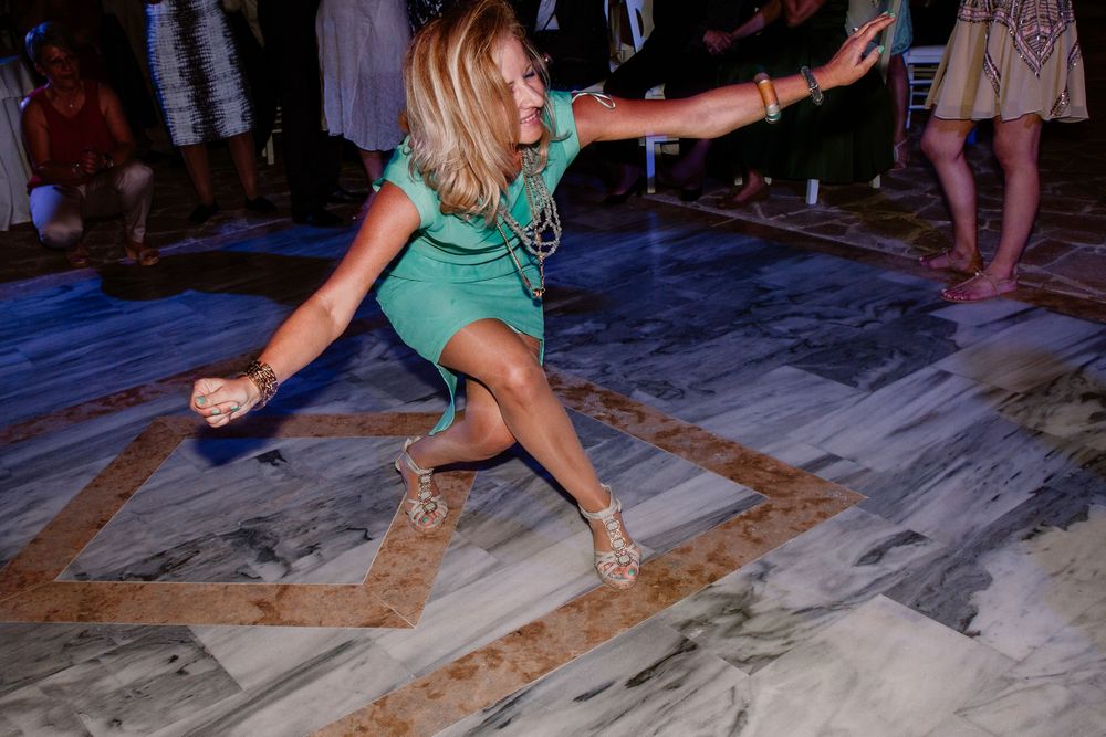 Woman in green dress dancing energetically on marble dance floor at a party event.