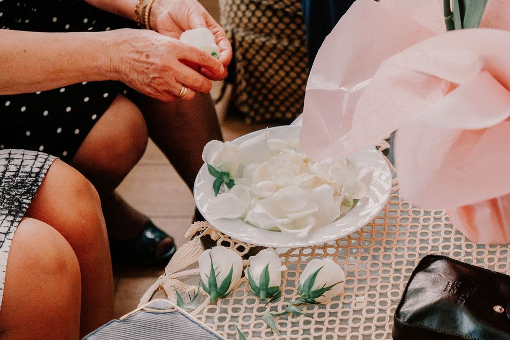 Close-up of white flower petals in a decorative bowl surrounded by small floral cards at a wedding celebration.