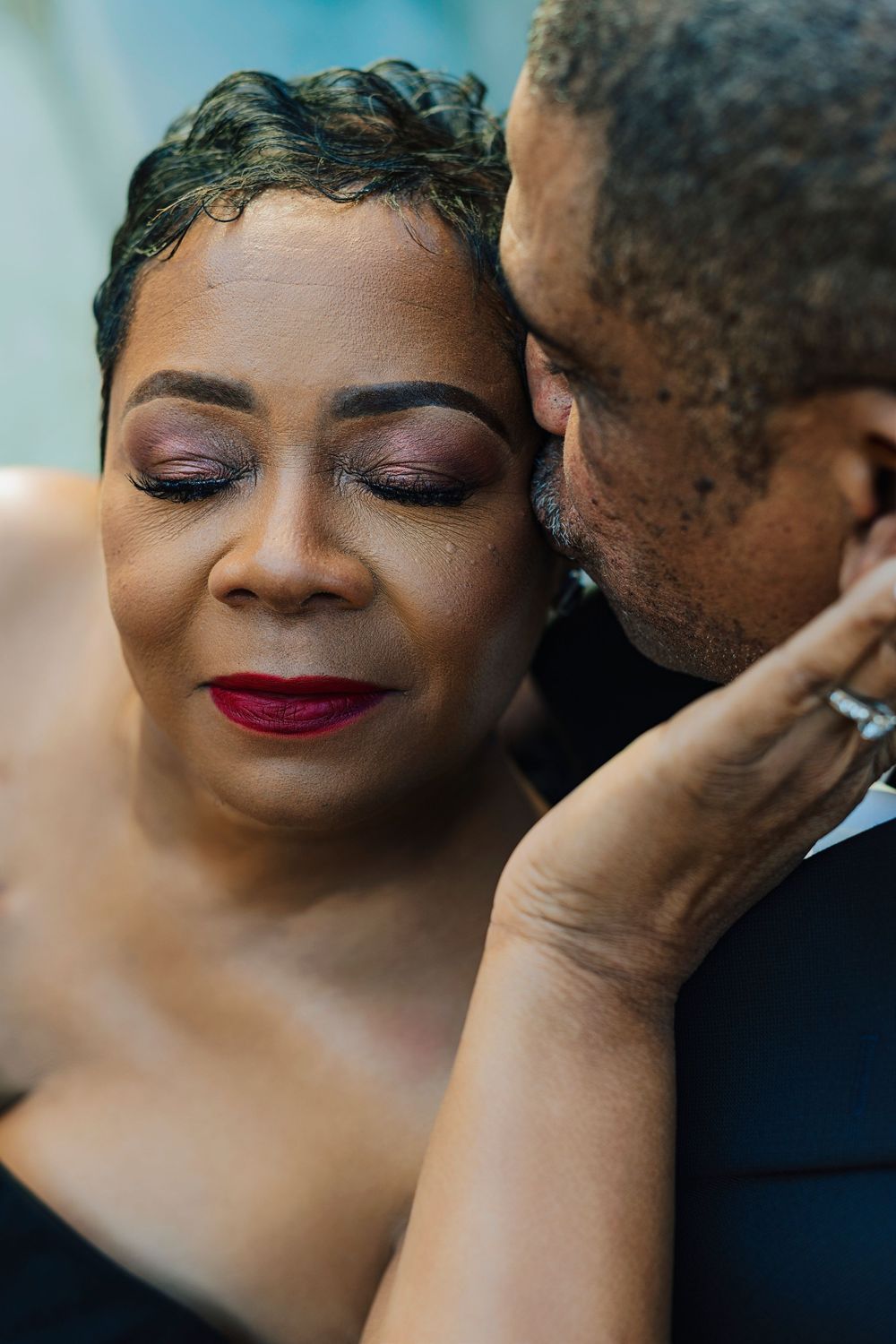 A romantic couple shares an intimate moment, woman with red lips and closed eyes as man leans in close.