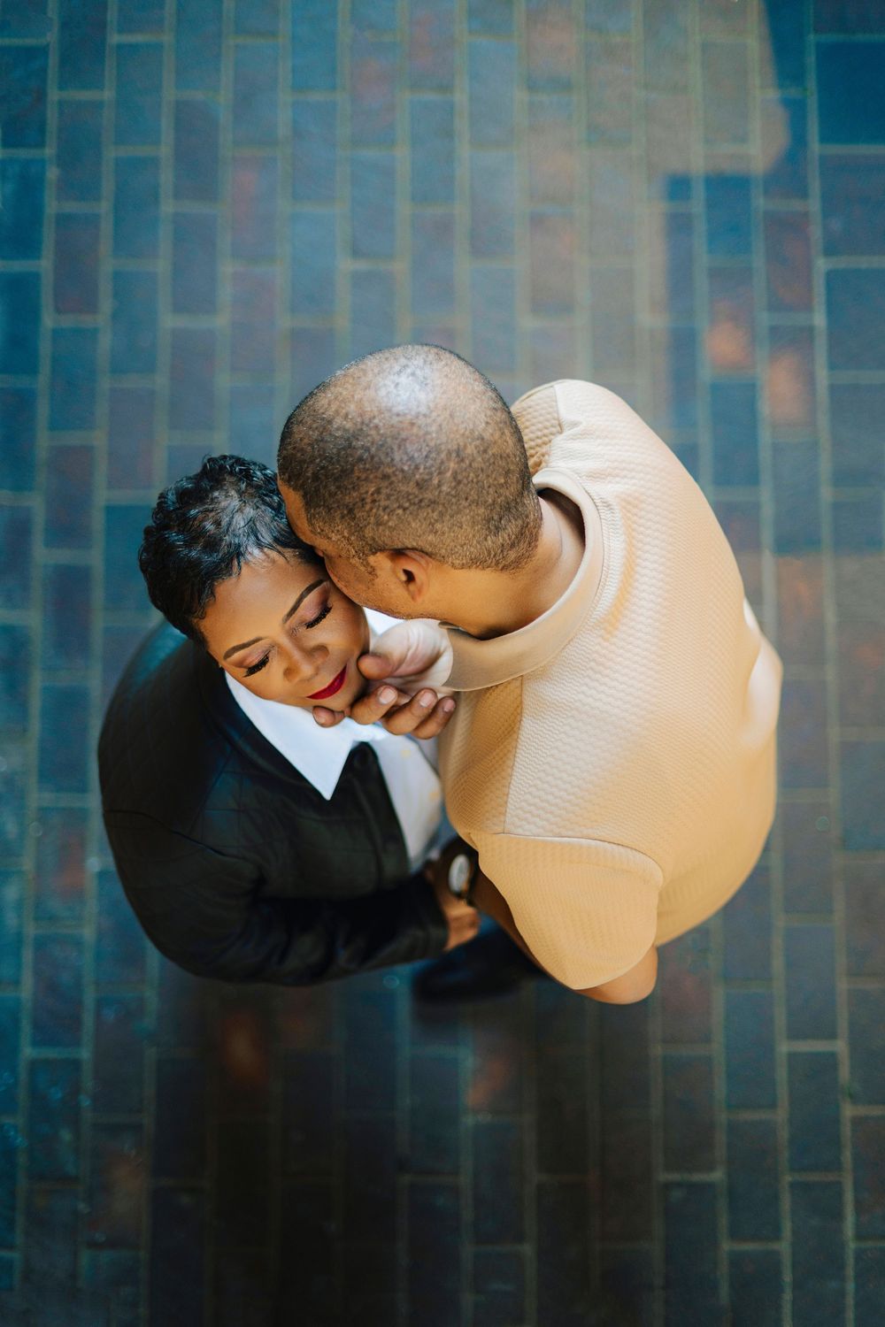 Romantic aerial view of a couple embracing tenderly on a blue brick floor.