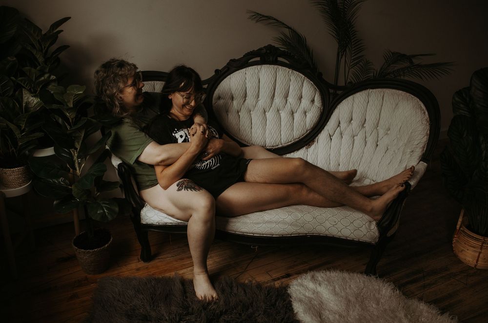 Couple relaxing together on a vintage white tufted sofa surrounded by lush indoor plants in a cozy room.