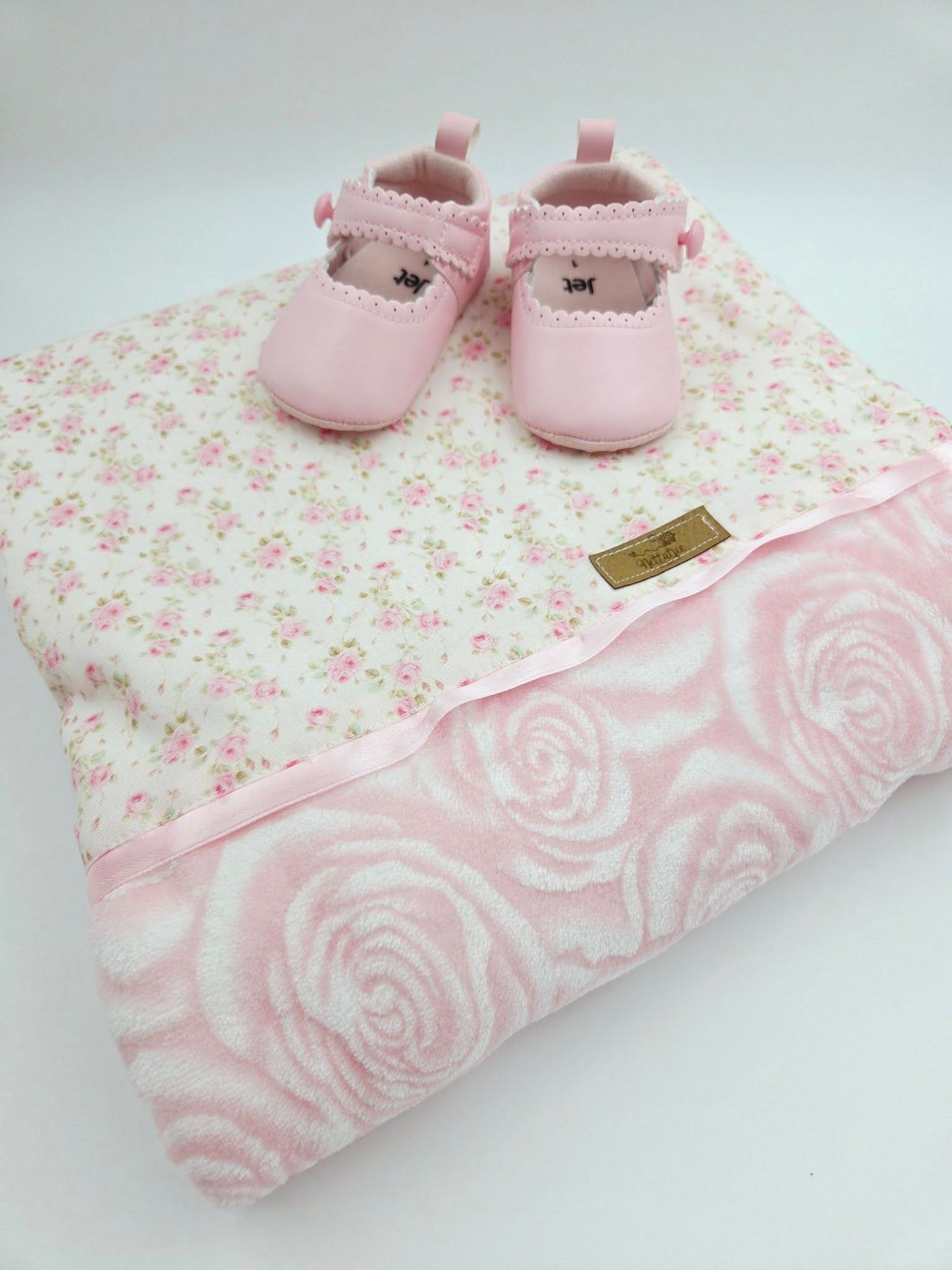 Soft mint minky dot baby blanket with pink floral fabric and pink baby shoes on top.