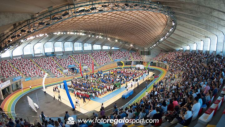 Vista panorámica de un pabellón deportivo cubierto repleto de gente, con asientos coloridos y un gran evento deportivo en marcha.