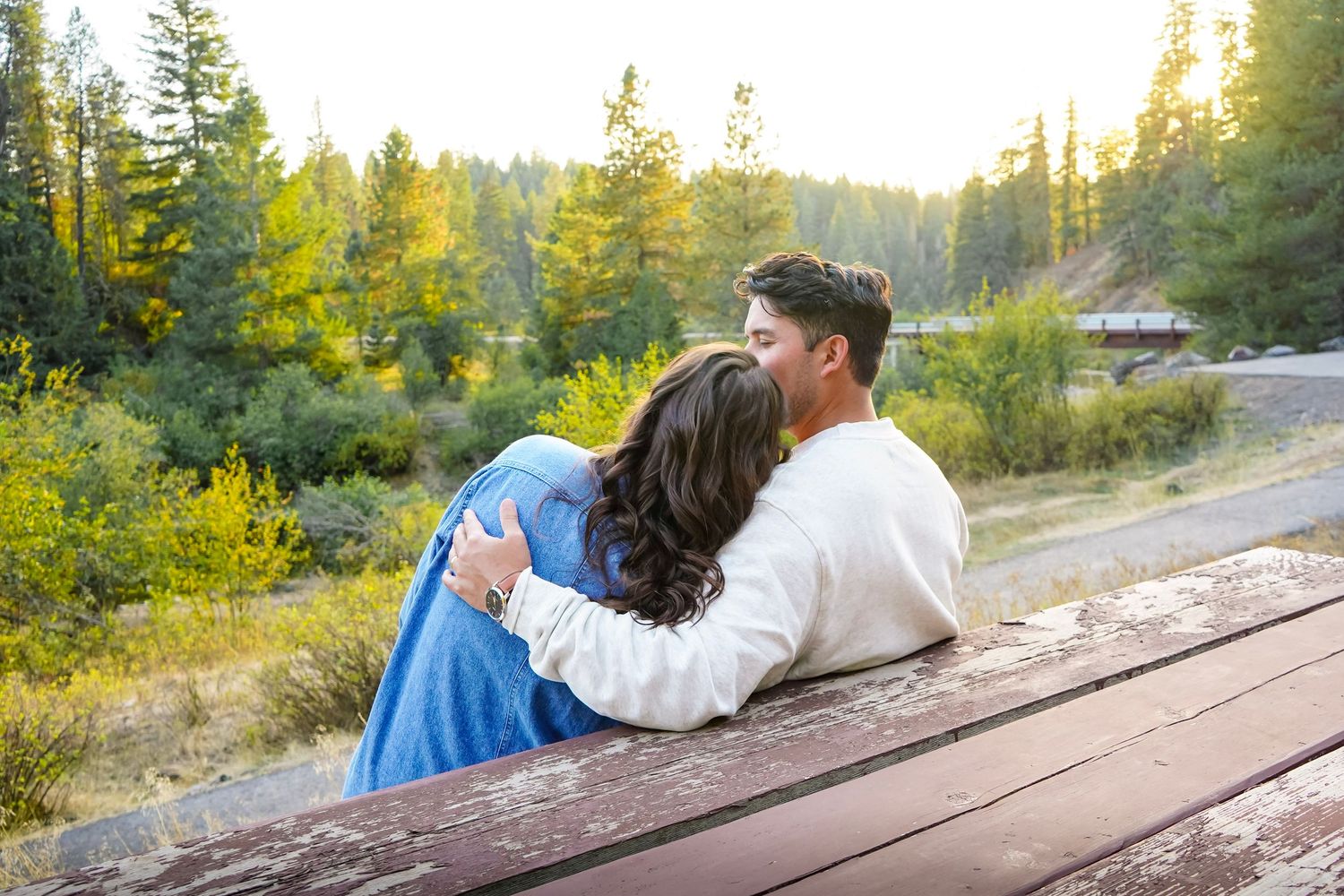 Couple holding hands and running on a forest trail, woman in red dress and boots, man in white sweater and jeans.