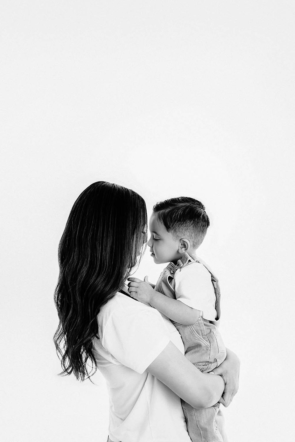 A black and white portrait of a mother tenderly holding her young son close.