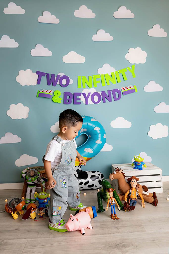 A toddler boy celebrates his 2nd birthday with Toy Story themed decorations and toys.