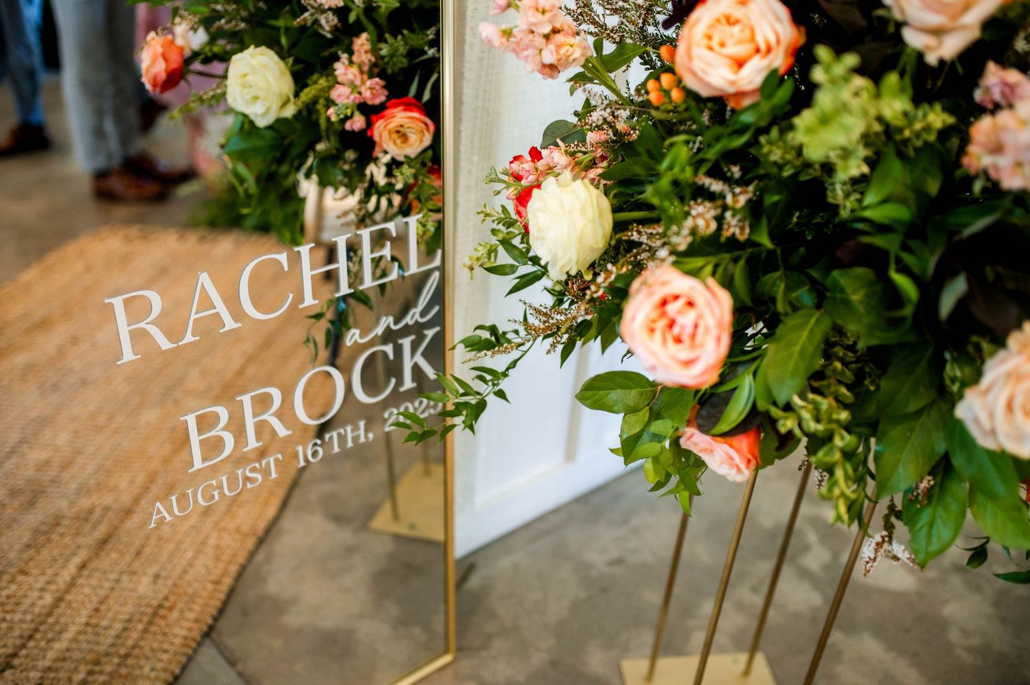 Wedding welcome sign reading Rachel and Brock August 16th adorned with lush floral arrangements.