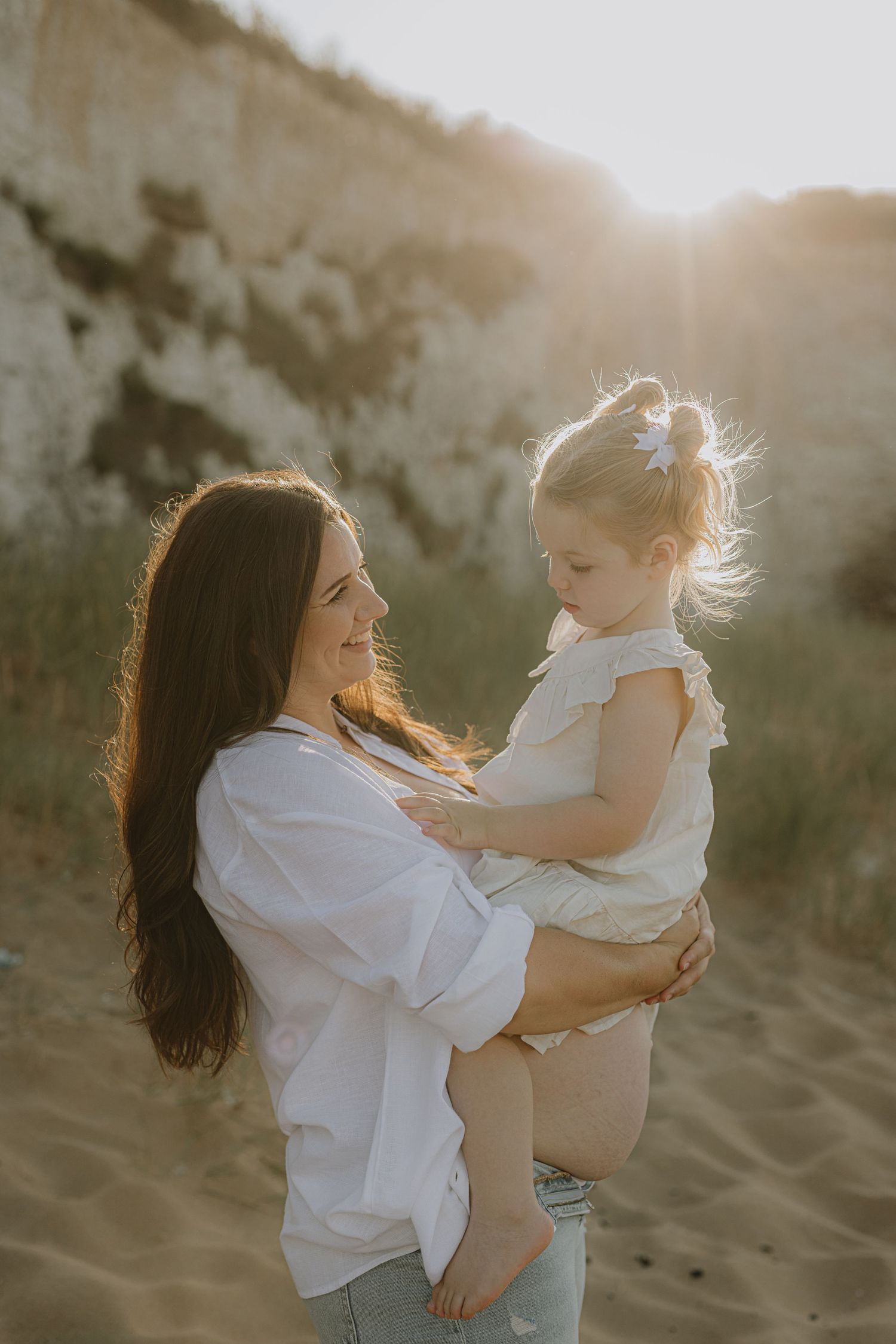 Joyful interaction between parent and child playing on a beach at sunset.