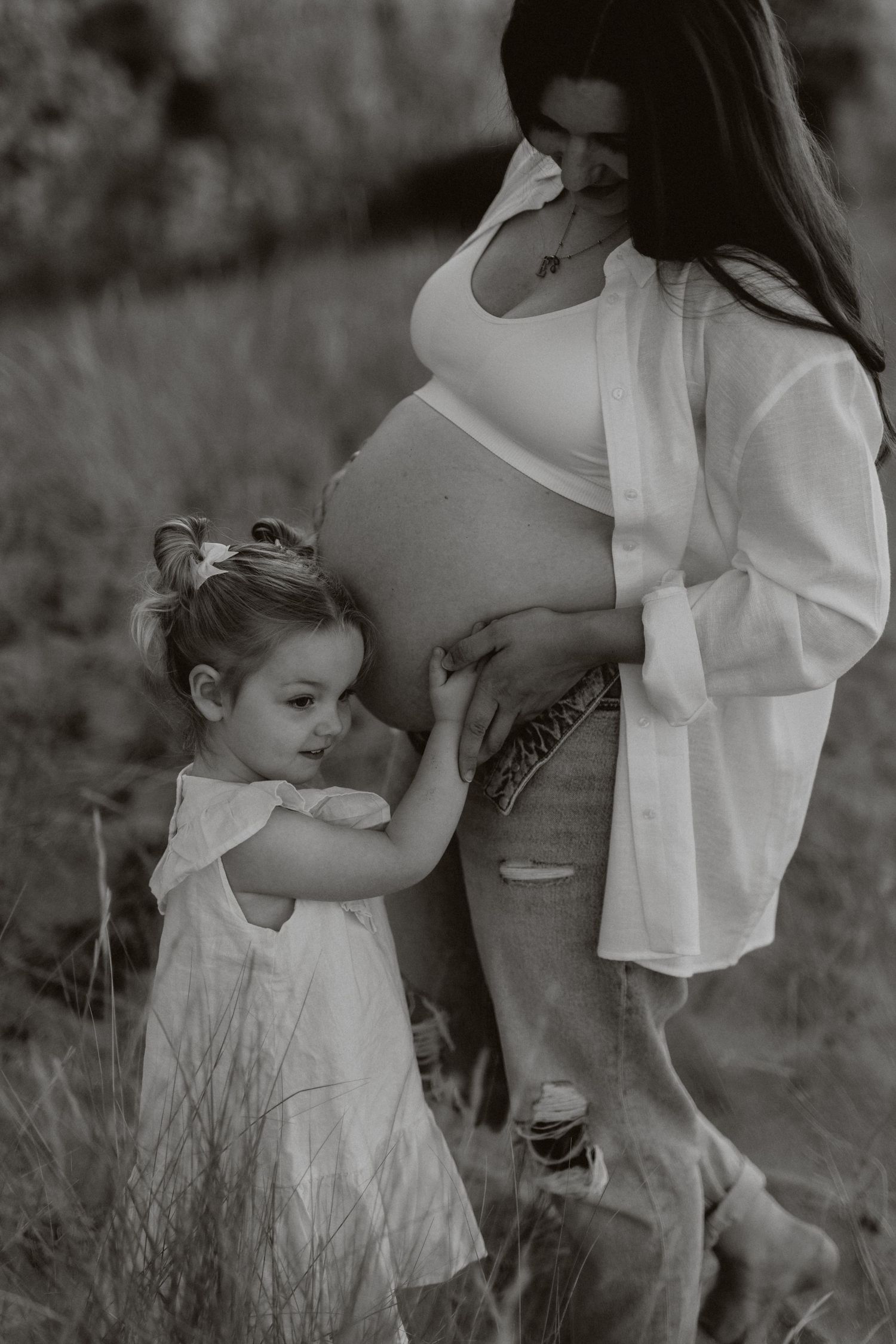 Black and white photo of a tender family moment on a grassy hillside.