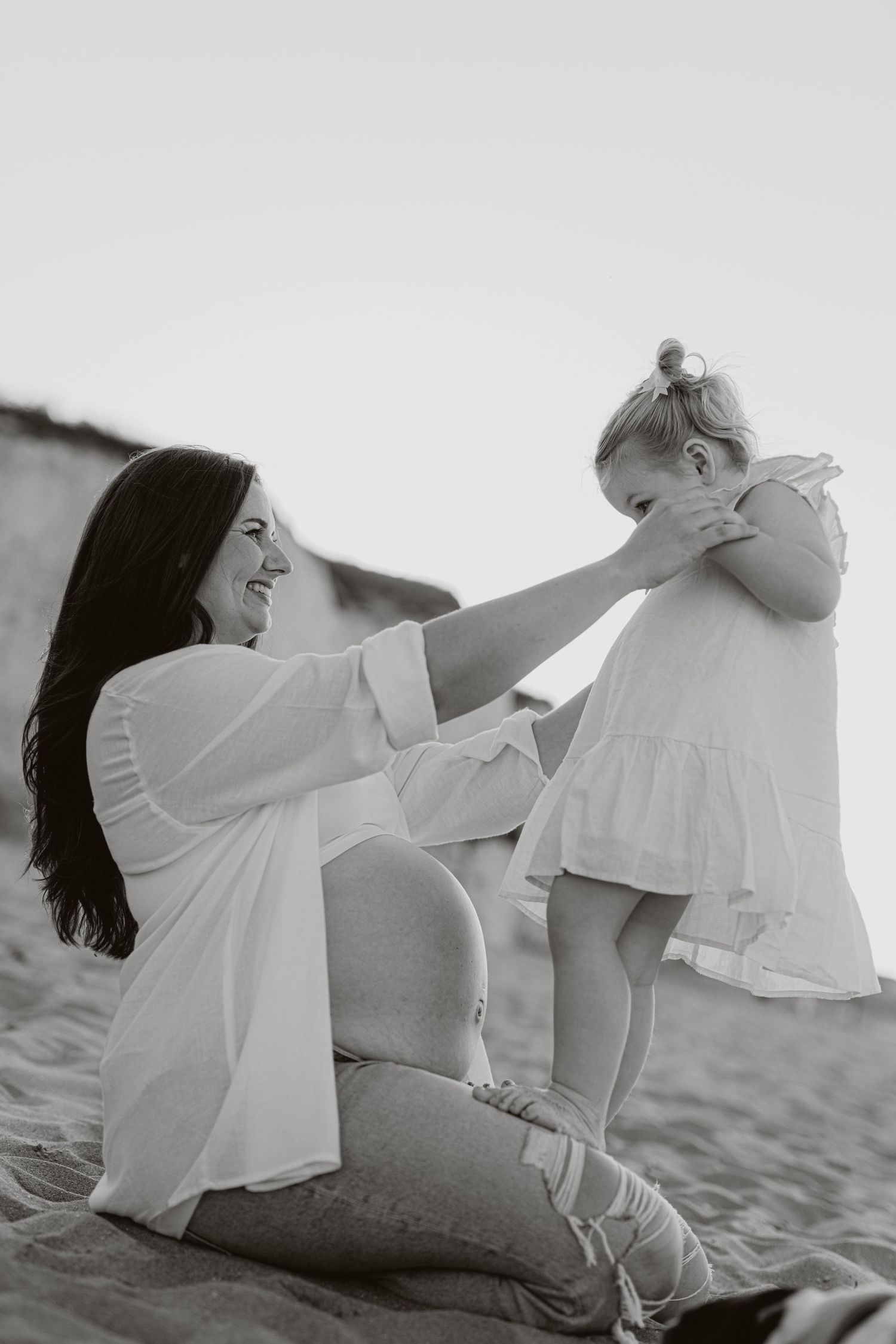 Black and white photo capturing a playful family moment on sandy beach.