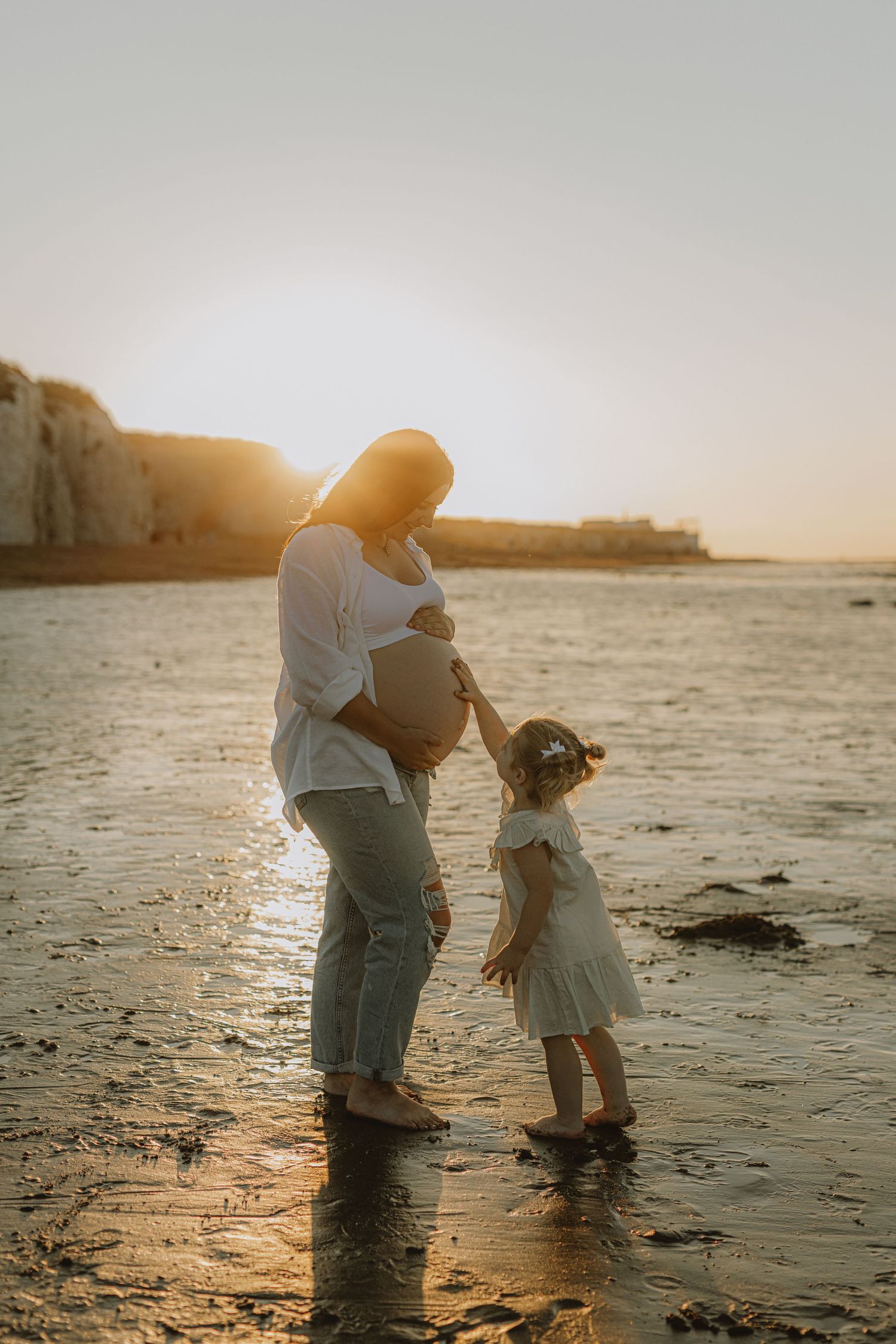 Parent and child playing together at sunset on a sandy beach.