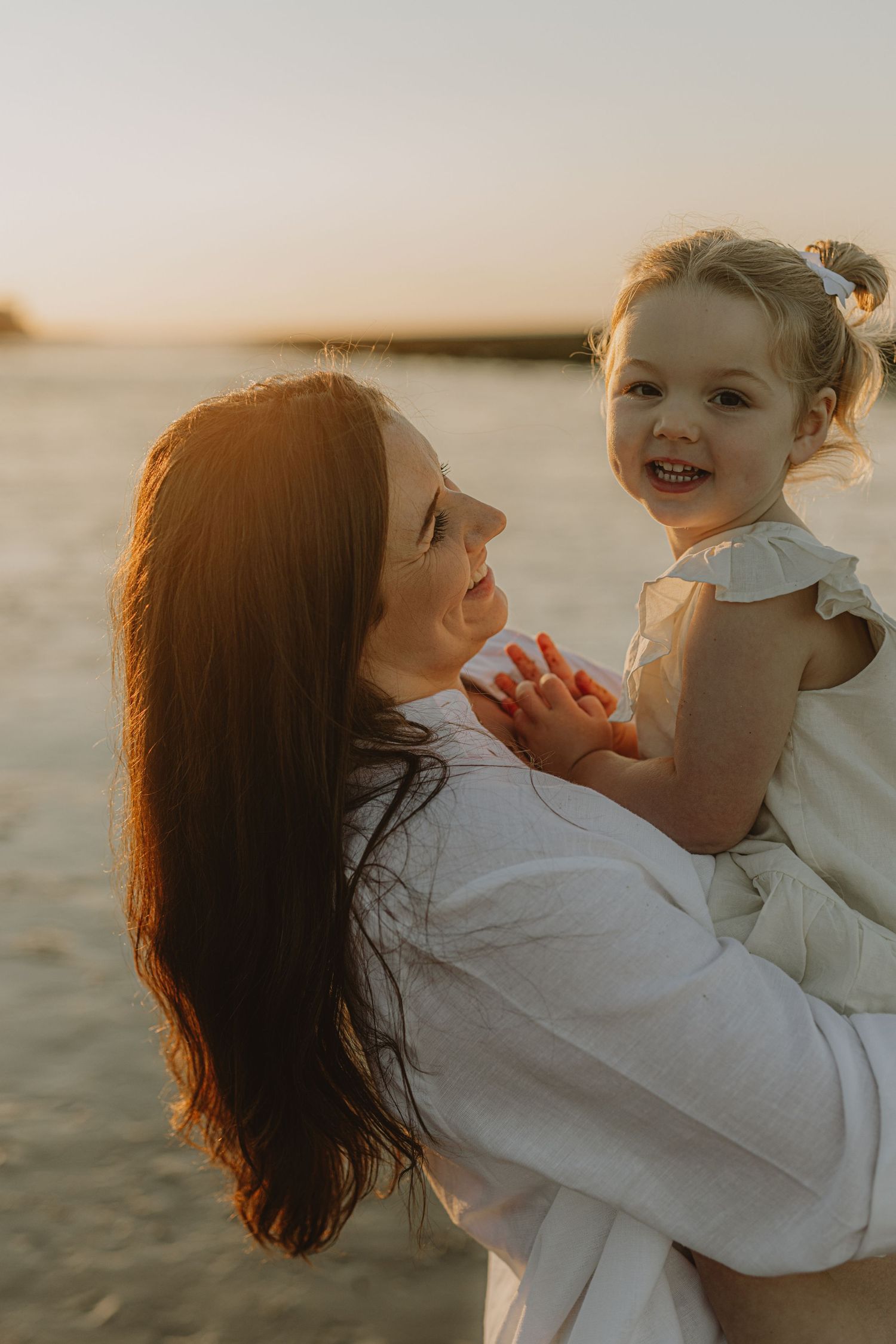 Joyful moment between two people laughing together at sunset by the ocean.