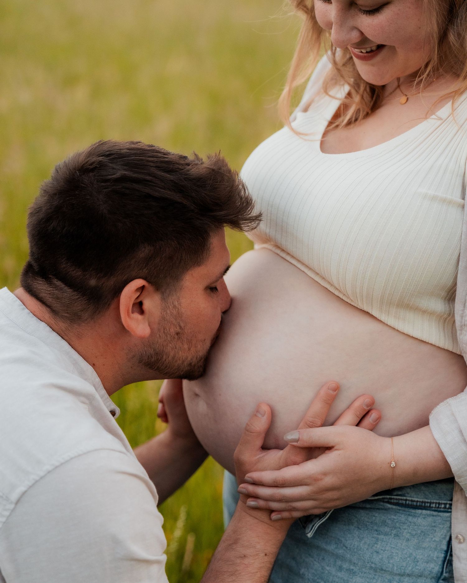 Paar läuft Hand in Hand über eine Wiese am Chiemsee, liebevoller Moment beim Babybauchshooting