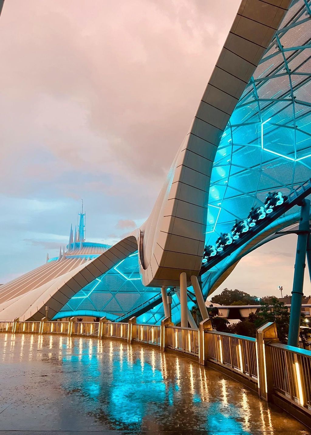 A modern bridge with illuminated blue lights reflects on calm waters at twilight.