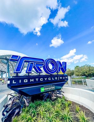 Tron Lightcycle Power Run coaster signage with sleek blue metal design at Magic Kingdom theme park entrance.