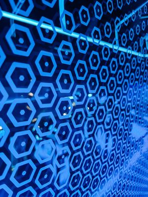 Repeating pattern of glowing blue hexagonal shapes creates an abstract geometric background with a technological feel.
