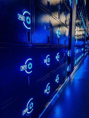 A row of illuminated blue circular neon lights mounted on dark metal lockers creates a futuristic industrial atmosphere.