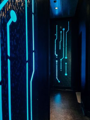 Futuristic hallway with glowing blue circuit patterns on dark walls creating a cyberpunk aesthetic.