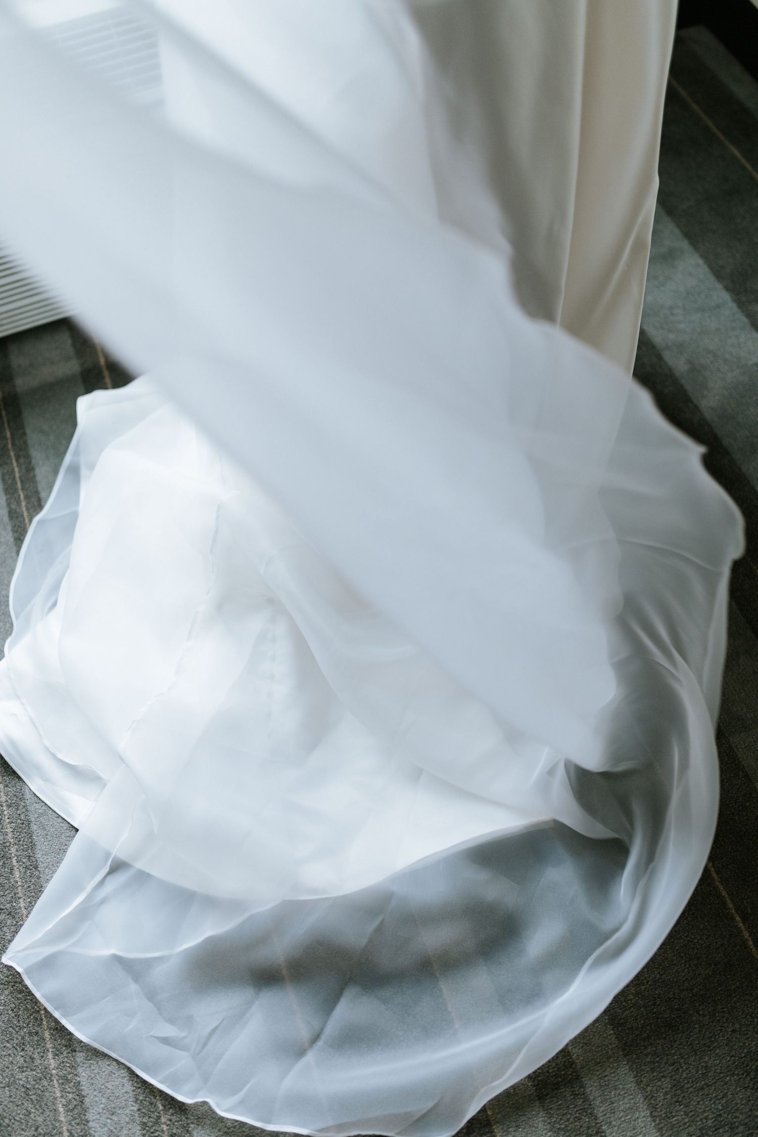 Close-up detail of flowing white wedding dress fabric creating elegant folds and layers.