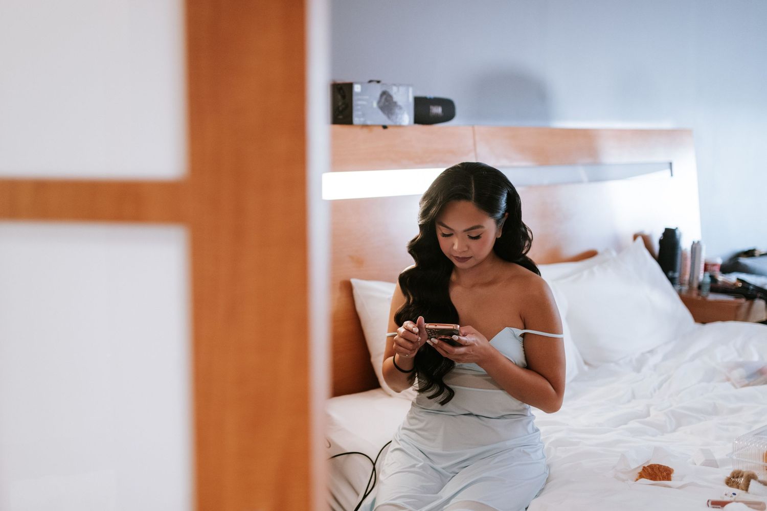 Candid moment of wedding preparation while checking phone in bed.