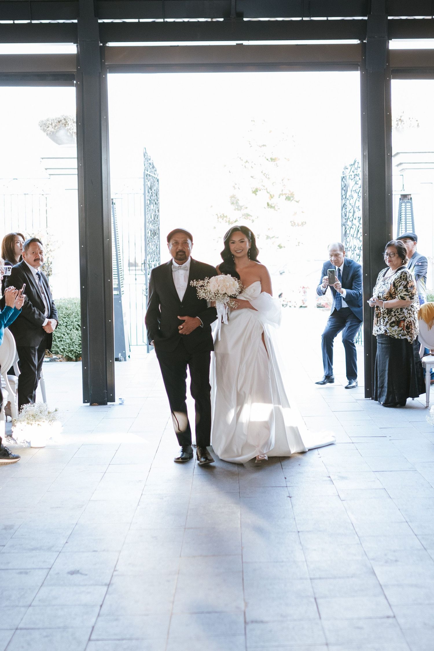 A couple makes their grand entrance through glass doors at their wedding celebration.