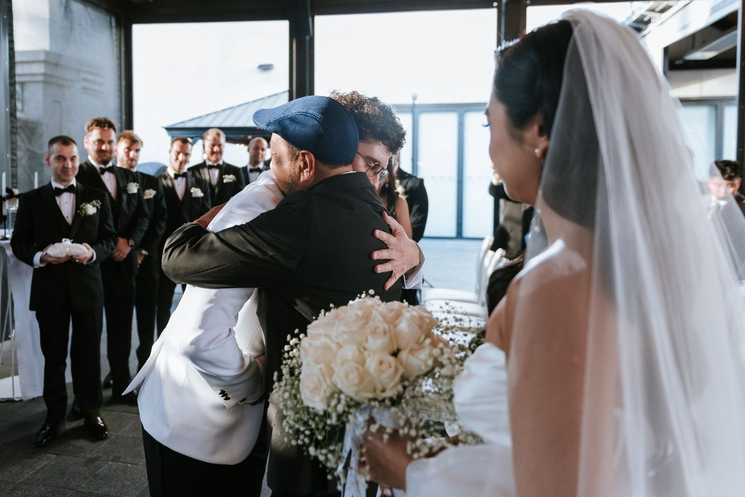 A touching moment at a wedding as guests watch the couple embrace near floral arrangements.