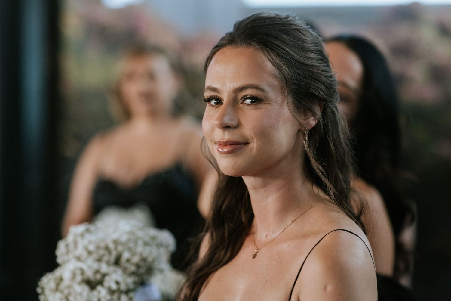 A bridesmaid in a pink dress smiles during the wedding celebration.