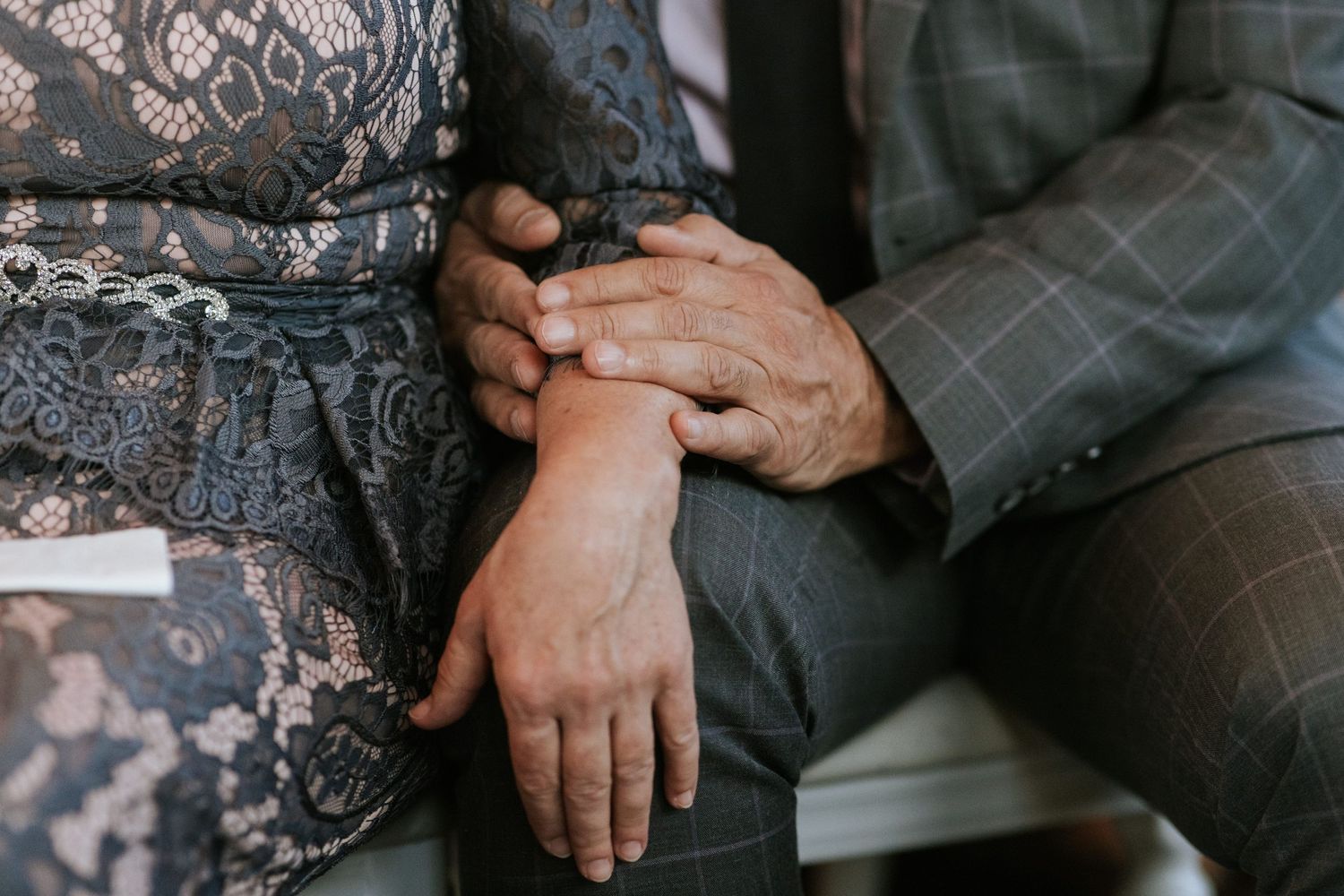 Close-up detail of hands touching during an intimate wedding moment.