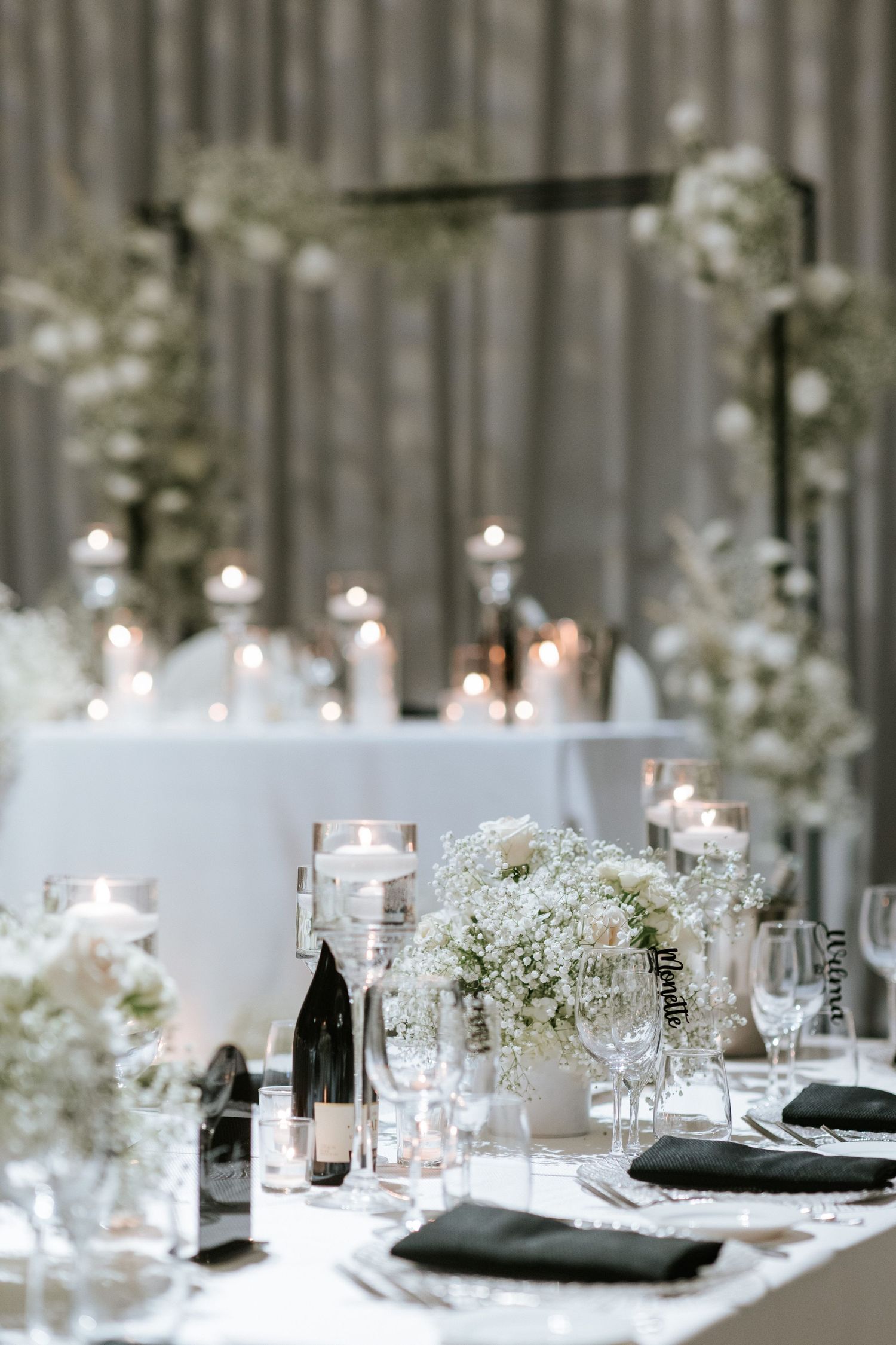 Elegant white wedding reception table setting with candles, flowers and modern decor.