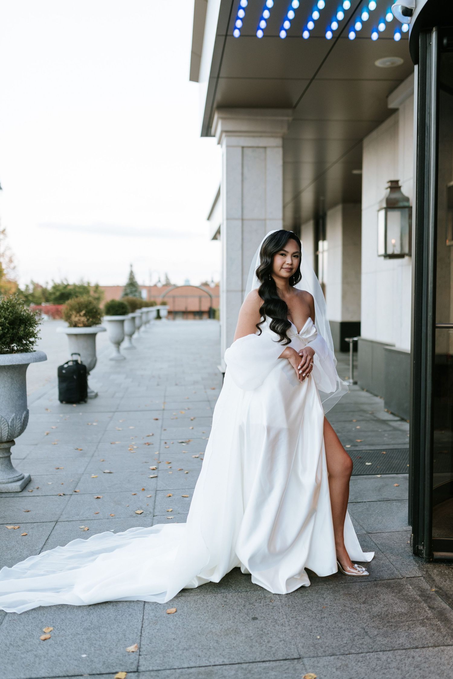Elegant white wedding gown with dramatic train and slit detail on outdoor terrace.