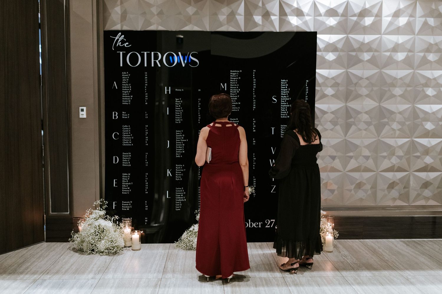 Two people stand in front of a black step-and-repeat banner at an event.