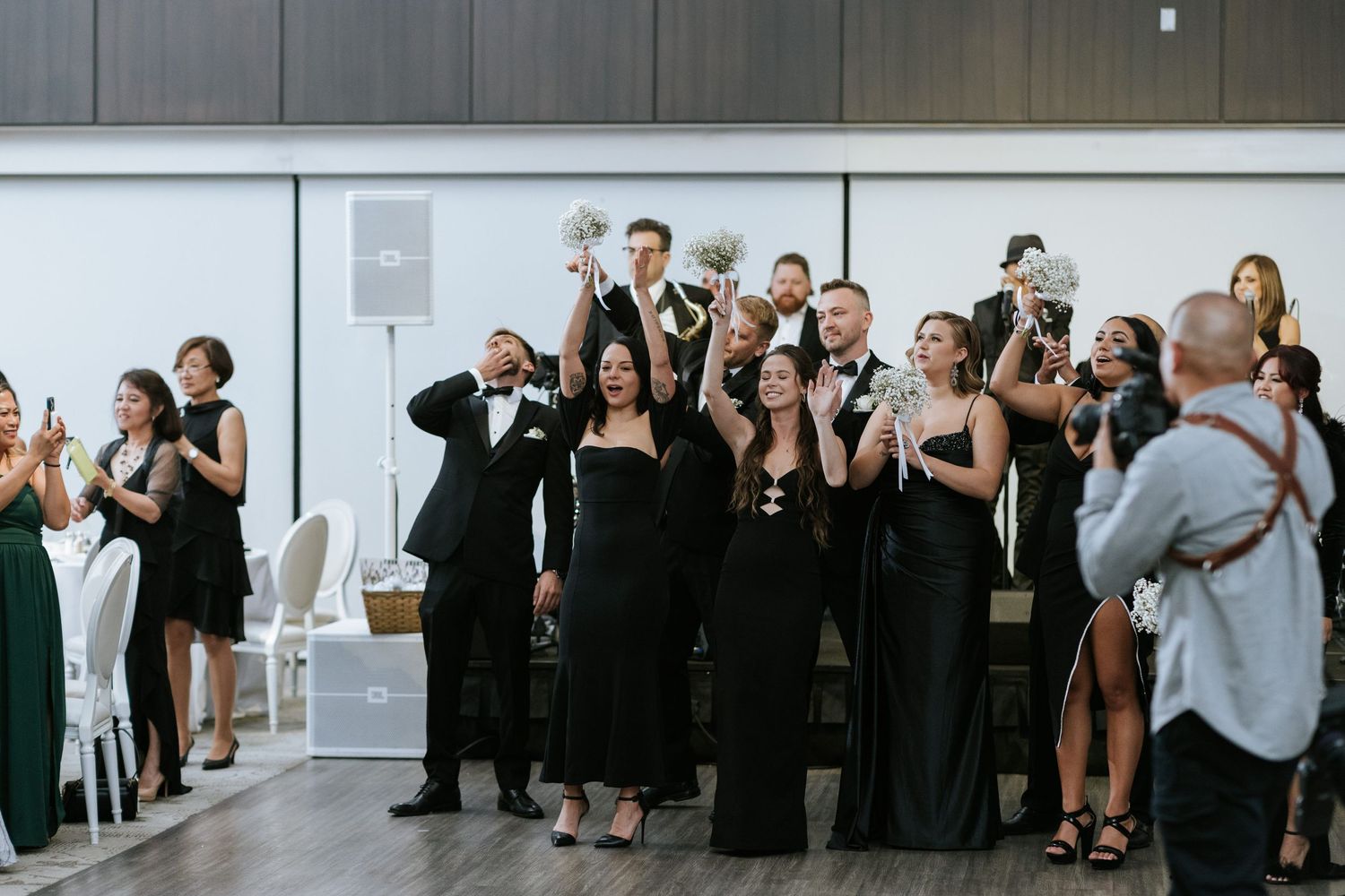 Wedding guests in formal attire taking photos with phones during reception.