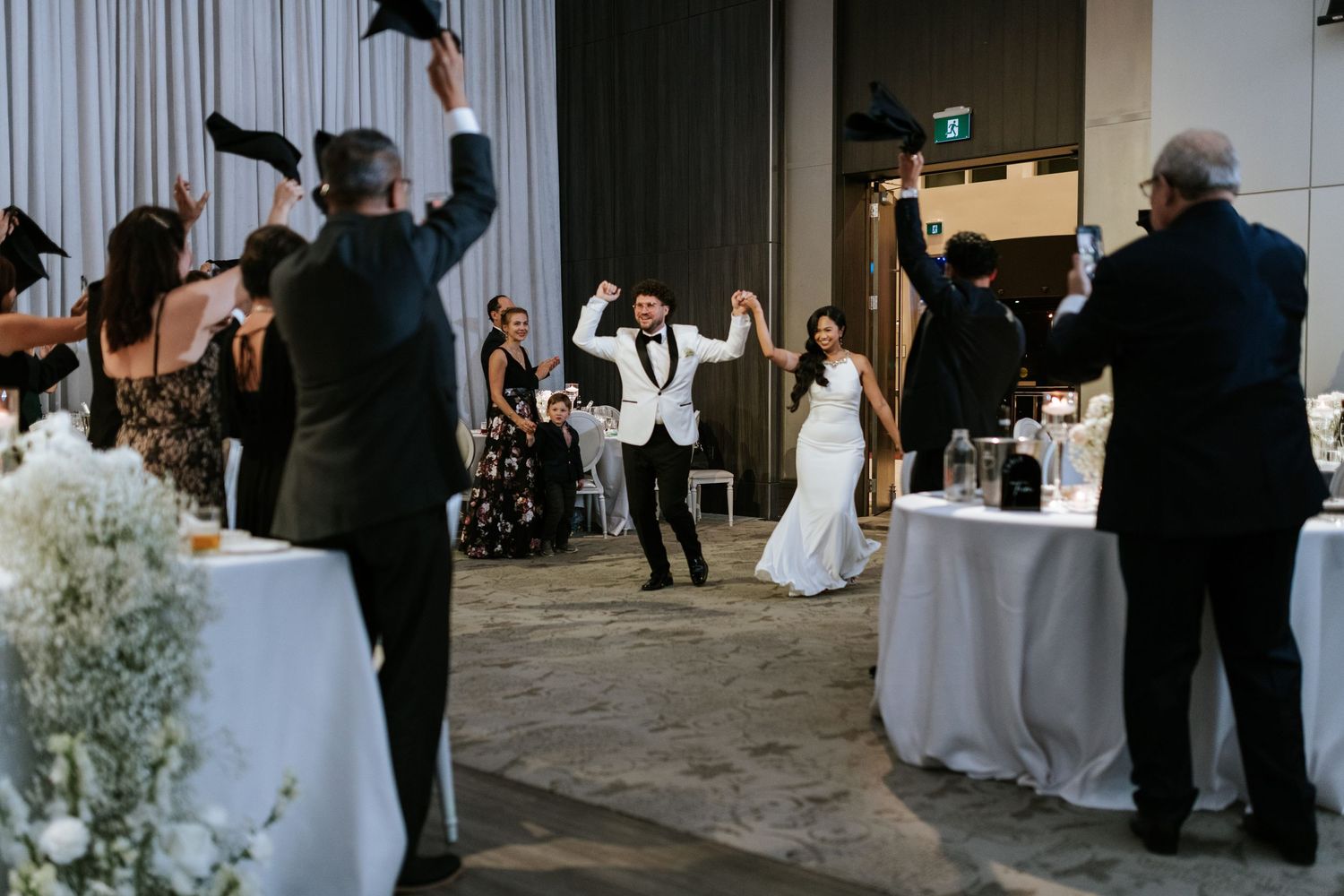 Celebration at wedding reception with guests cheering and dancing.