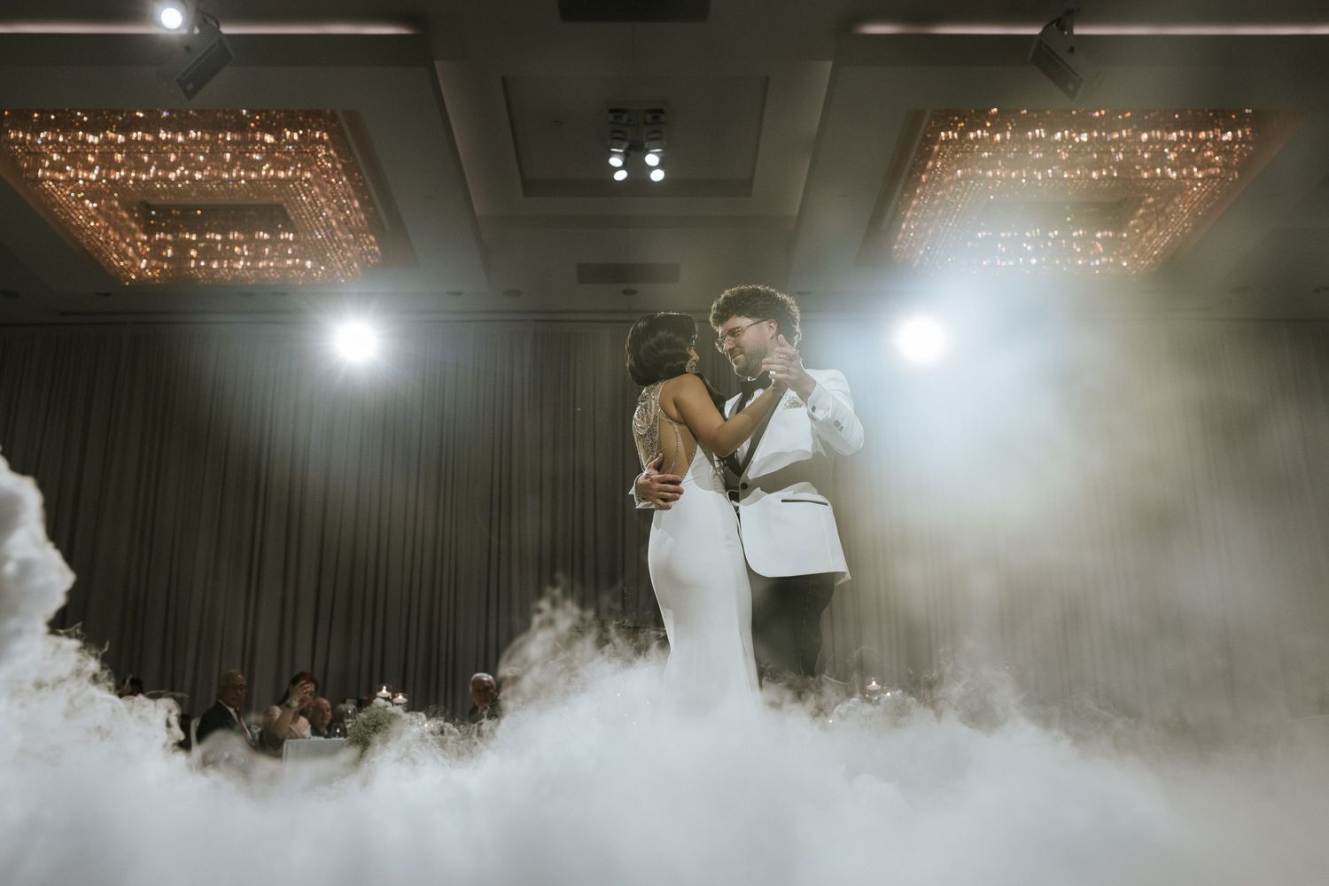 A romantic first dance moment captured with dramatic fog effects and overhead lighting at a wedding reception.