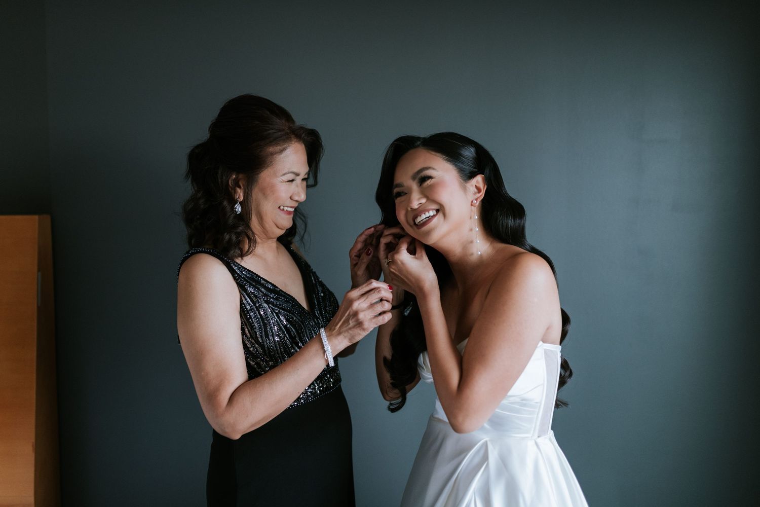 Two people share a joyful moment while getting ready in formal attire.