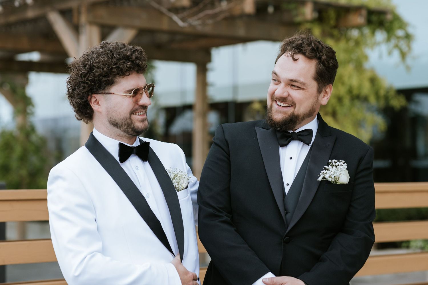 Two people in formal wear share a moment on an outdoor wooden deck.