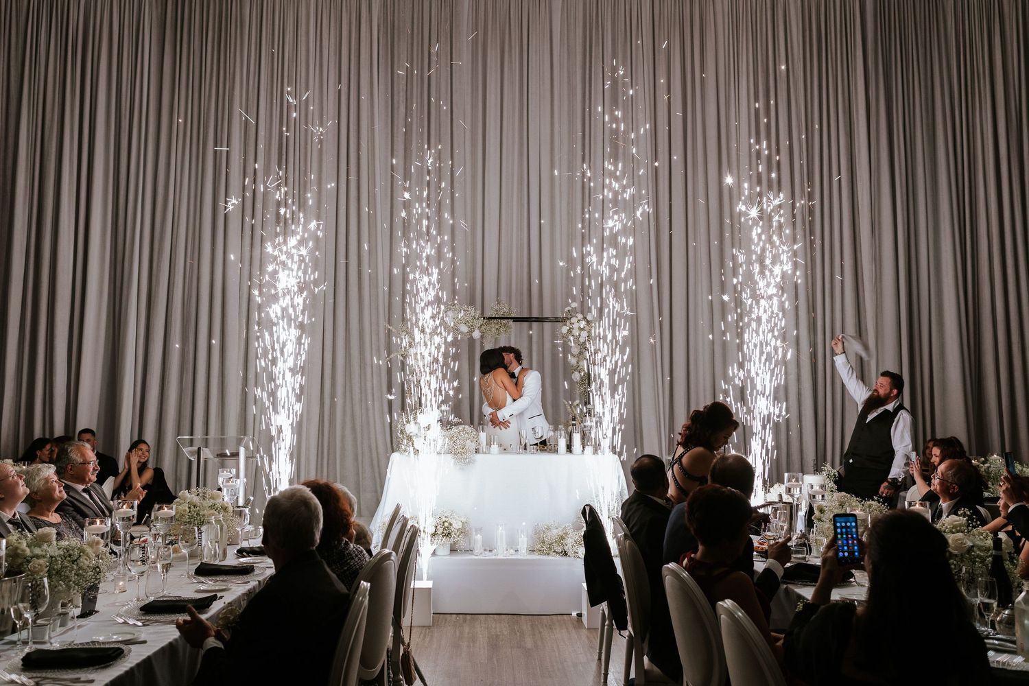 Wedding reception venue decorated with sparkling pyrotechnic effects and elegant table settings.